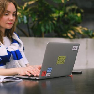 Young woman with a laptop working in a modern indoor space, showcasing freelance and digital nomad lifestyle.