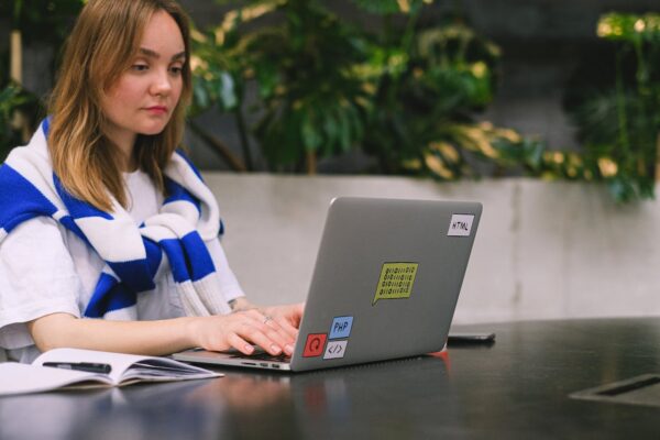 Young woman with a laptop working in a modern indoor space, showcasing freelance and digital nomad lifestyle.