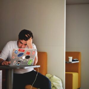 Man showing stress and frustration while working remotely on a laptop indoors.